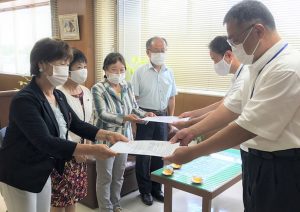 堂山市長公室長(右)と高井教育次長(左)に要望書を手渡す議員団